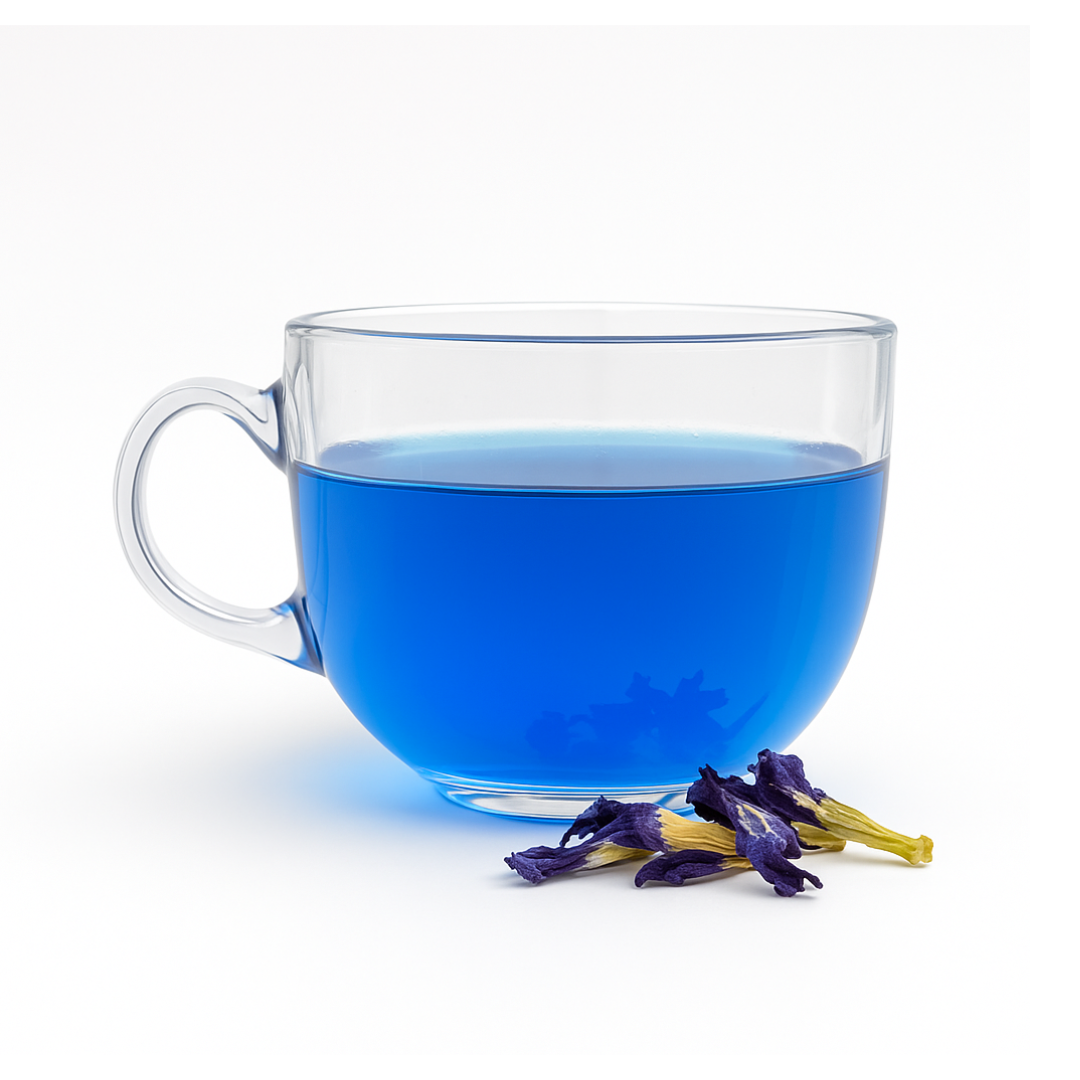Clear glass mug filled with blue liquid next to butterfly pea flowers on a white background
