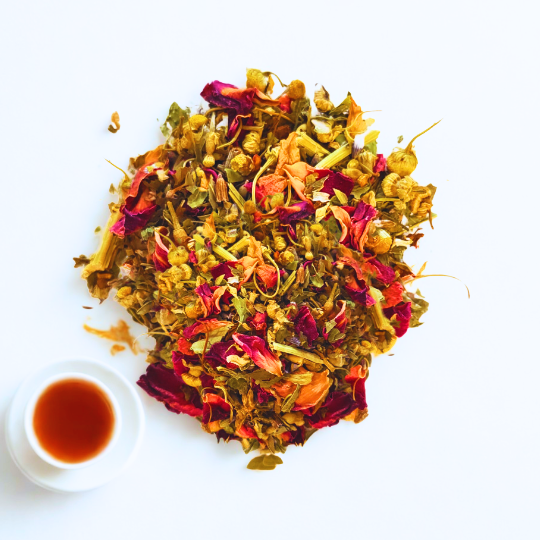 Colorful dried tea leaves on a white background with a small cup of tea.