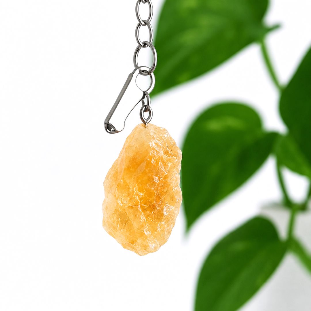 Citrine crystal pendant on a chain with green leaves in the background