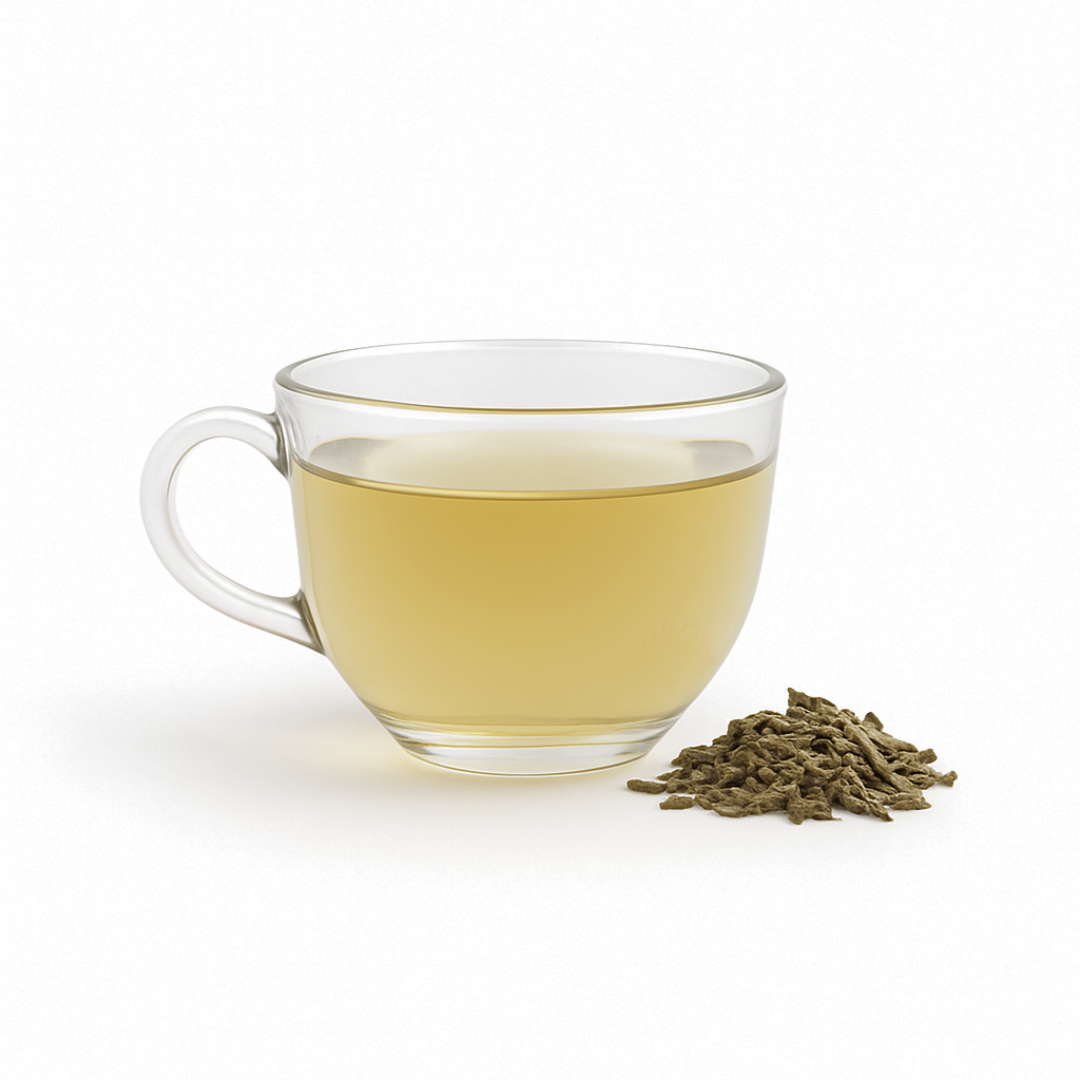 Clear glass mug filled with green tea and a pile of green tea leaves on a white background