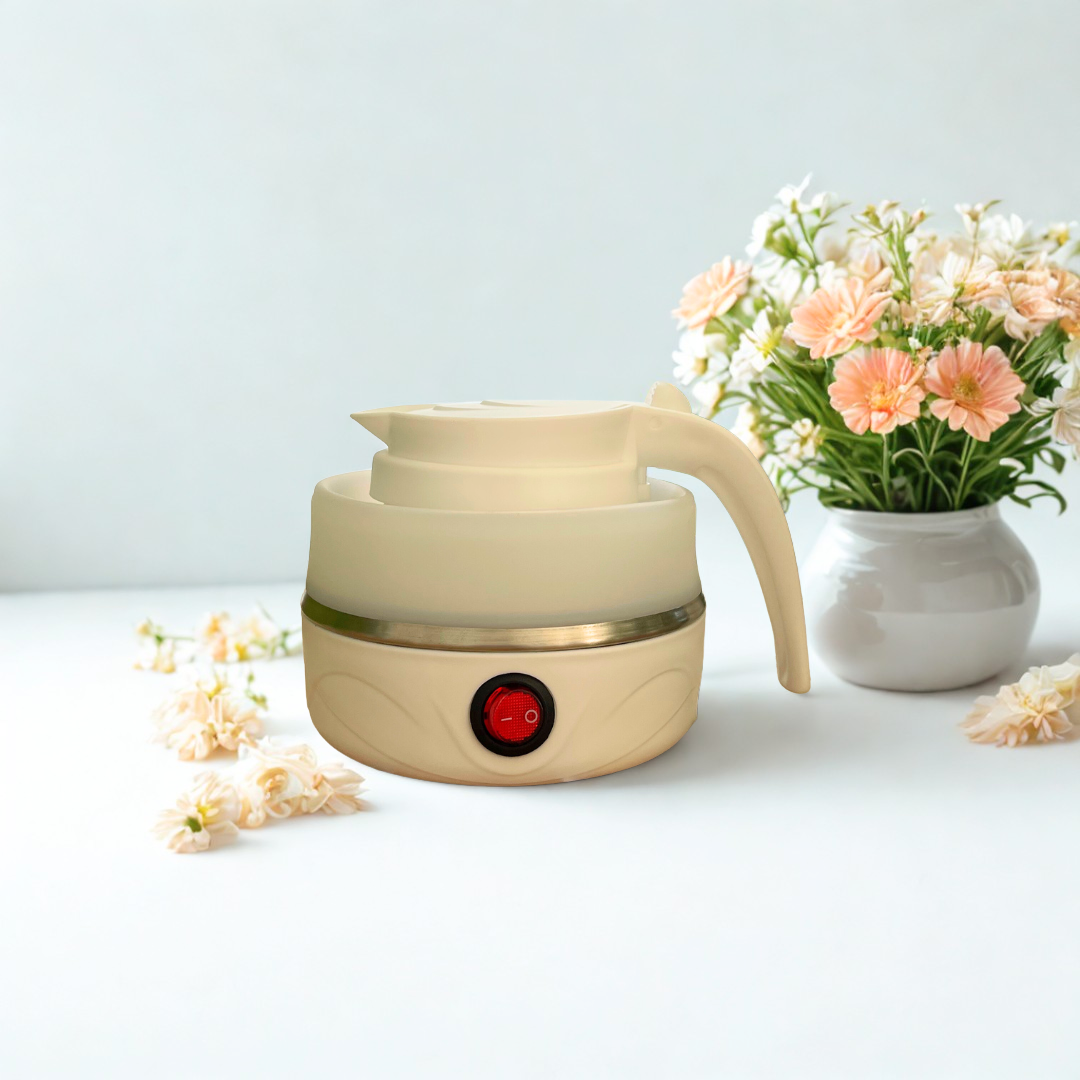 Cream-colored electric kettle on a light surface with flowers in the background