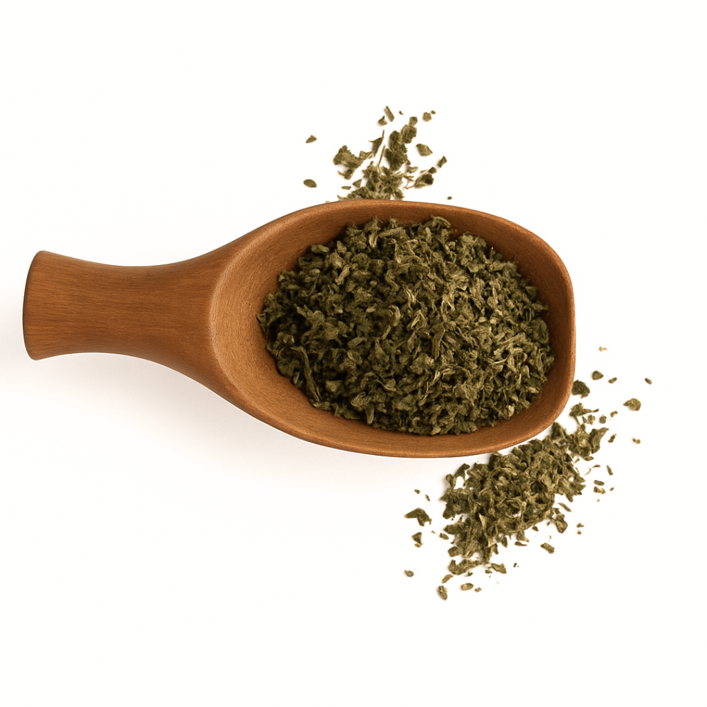 Wooden spoon filled with green leafy substance on a white background