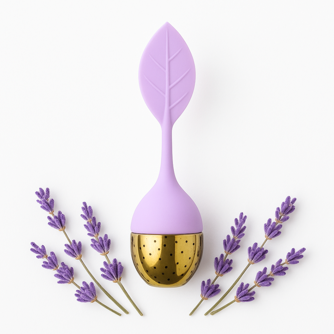 Purple leaf-shaped tea infuser with gold interior, surrounded by lavender flowers on a white background