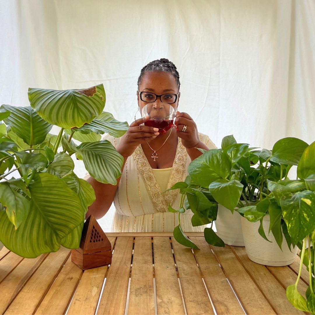 Woman drinking red wine in a room with plants