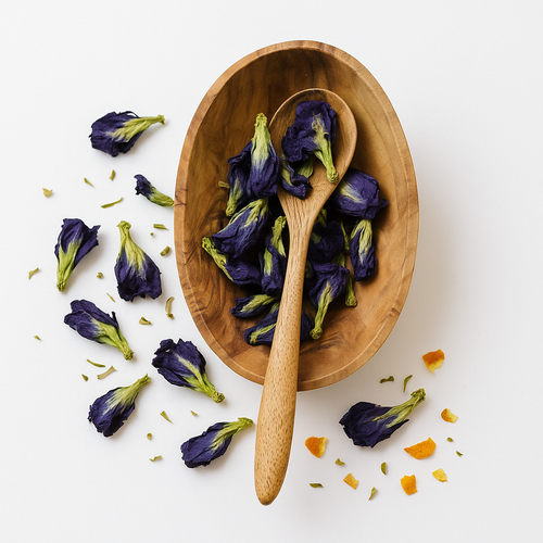 Wooden bowl and spoon filled with dried butterfly pea flowers on a white background