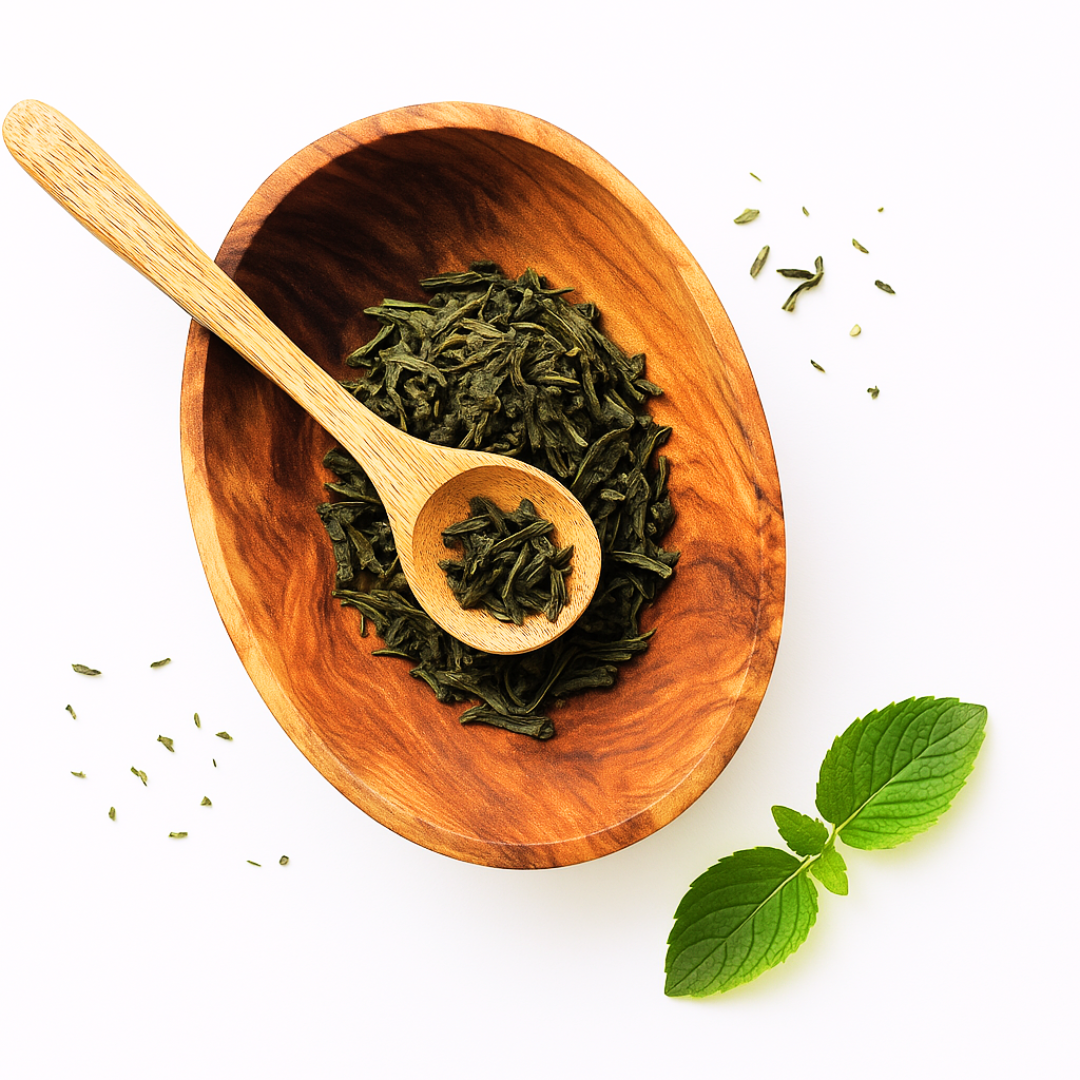 Wooden bowl with green tea leaves and a wooden spoon on a white background