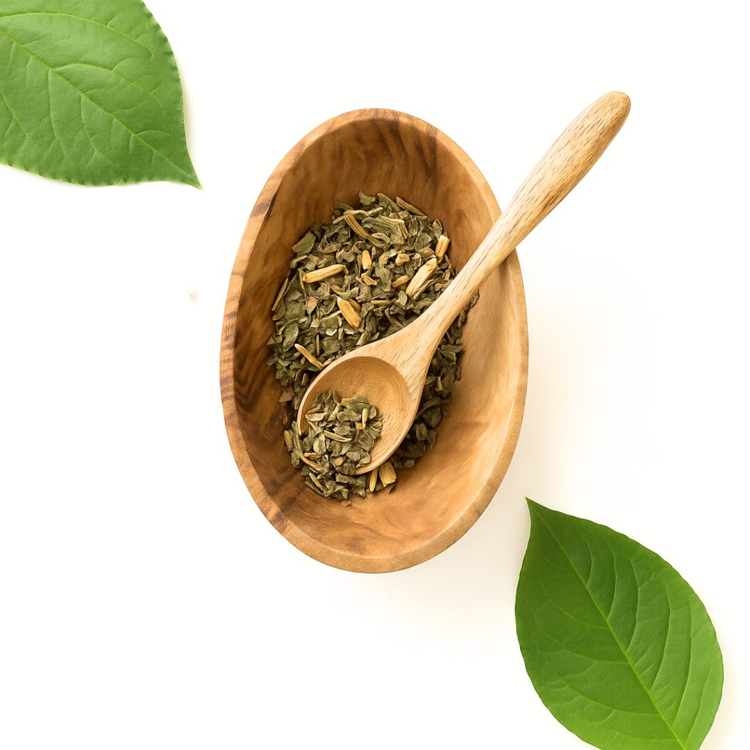 Wooden bowl with dried herbs and a wooden spoon on a white background with green leaves.