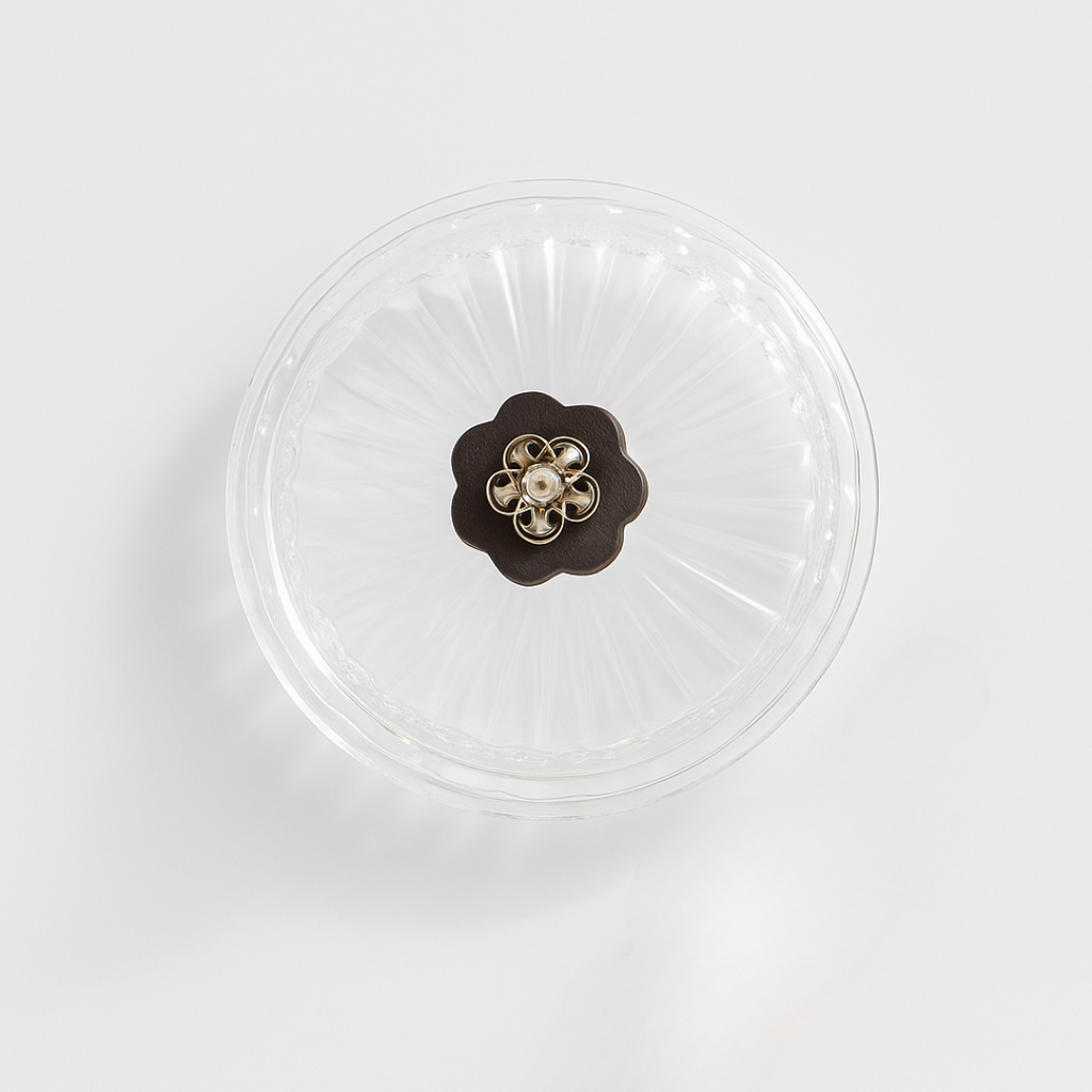 Clear glass lid with a decorative brown flower-shaped handle on a white background